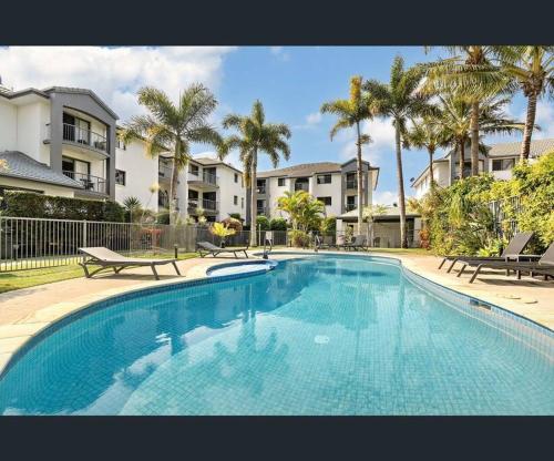 a large swimming pool with chairs and palm trees at Bilinga Bliss - Luxury beachfront apartment in Gold Coast