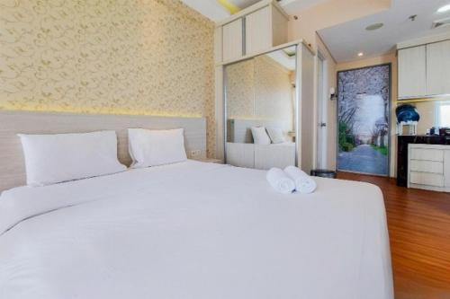 um quarto com uma grande cama branca com almofadas brancas em comfy corner studio apartment em Ciater-hilir