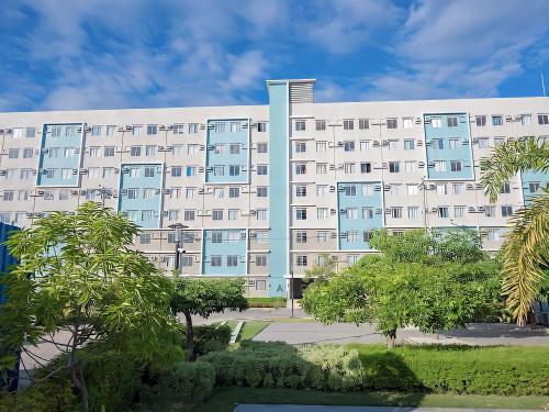 a large white building with trees in front of it at Affordable 2 Bed Condo Rental in Davao City with Wifi & Netflix, Swimming Pool, Gym & Billiard Hall in Davao City