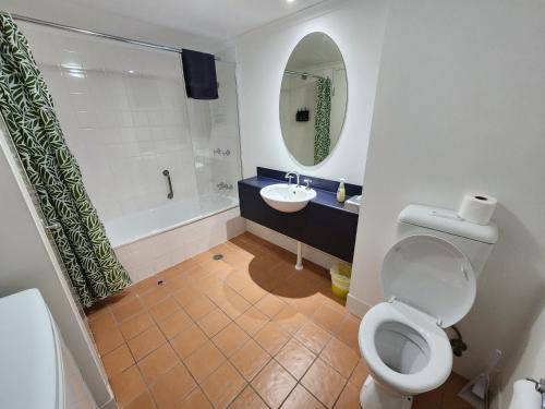 a bathroom with a toilet and a sink and a mirror at Canberra City Accommodation in Canberra
