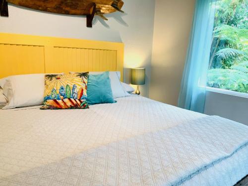 a bedroom with a white bed with a window at Puolani Iki-Sweet lil cottage near National Park in Volcano
