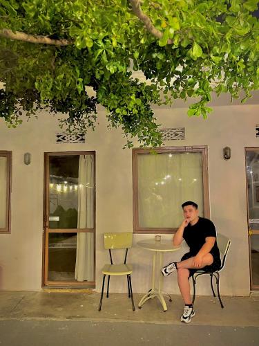 een man in een stoel naast een tafel bij Abahi homestay (giá rẻ ) in Xuan An