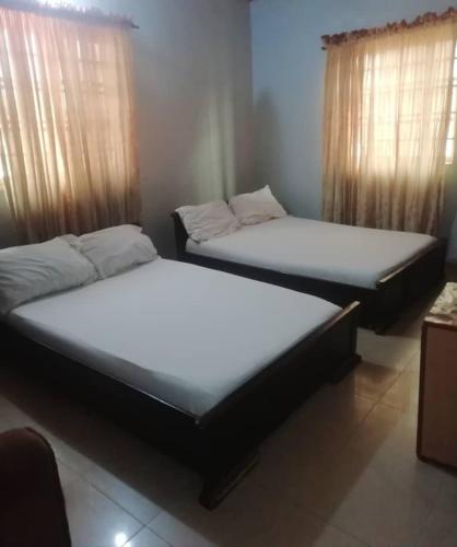 two beds sitting in a room with windows at Diamond Hotel close to Intl Airport, omole ikeja in Mawere