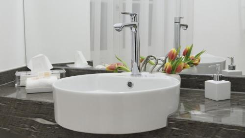 a bathroom with a white sink and flowers on a counter at City De Lights in Graz