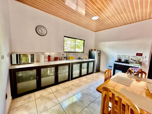 cocina con mesa y reloj en la pared en Casa Paraiso Tropical, en Parrita