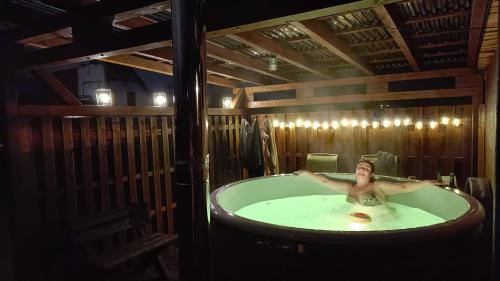 una mujer sentada en una bañera en una habitación en Pod klonem z Balią i Sauną, en Lubawka
