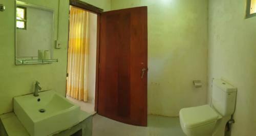 a bathroom with a sink and a toilet and a mirror at Rainforest River Edge in Deniyaya