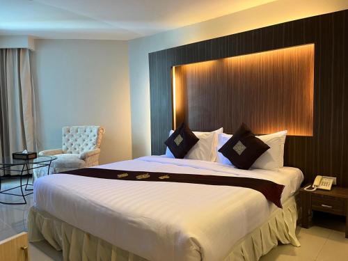 una camera d'albergo con un grande letto e una sedia di Suntara Wellness Resort & Hotel a Chachoengsao