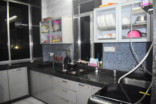 uma cozinha com armários brancos e um balcão preto em Prince Solo Hostel em Mumbai