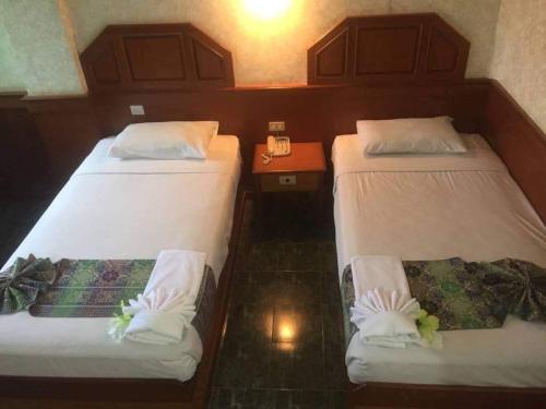 Sakol Grand Palace في محافظة ساكون ناخون: سريرين في غرفة في الفندق وعليها زهور