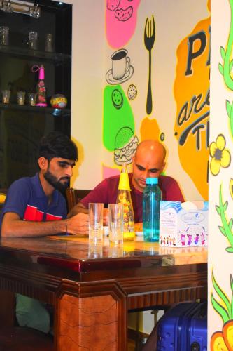 zwei Männer sitzen an einem Tisch in einem Restaurant in der Unterkunft Solo Hostel in Mumbai