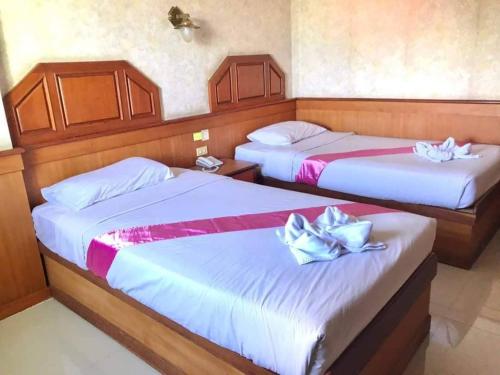 two beds in a hotel room with flowers on them at Sakol Grand Palace in Sakon Nakhon