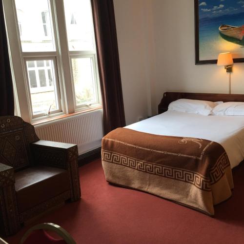 a bedroom with a bed and a chair and two windows at The Jericho Hotel in Oxford