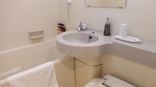 a white bathroom with a sink and a bath tub at Toyooka Sky Hotel in Toyooka