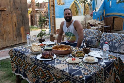 Ein Mann, der an einem Tisch sitzt und Essen drauf hat. in der Unterkunft A R A B I A Golden Palace in Luxor