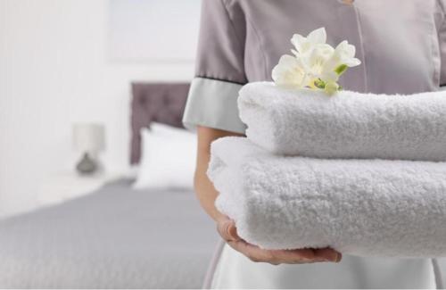 a woman holding a stack of towels in a hotel room at Hotel Raj vihar residency in Vijayawāda