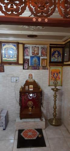 a room with a clock and pictures on the wall at Temple Darshan in Chidambaram