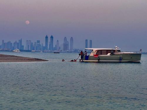 Stella Romana Yacht في دبي: قارب في الماء مع مدينة في الخلفية