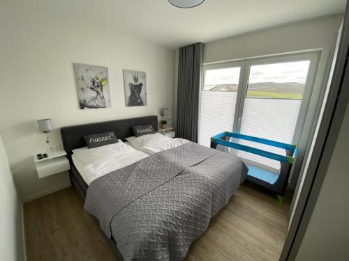 1 dormitorio con cama y ventana grande en Ferienhaus Sonnenweg 40 Diemelsee mit Sauna und Garten, en Diemelsee