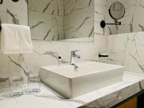 a bathroom with a white sink and a mirror at Regenta - The World Surat in Surat