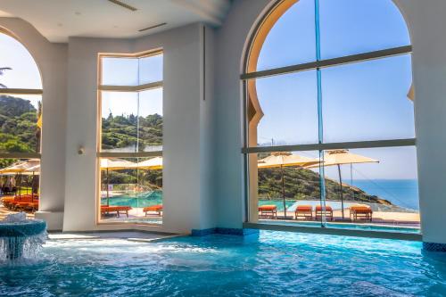 a pool with windows and a view of the ocean at Royal Tulip Korbous Bay Thalasso & Springs in Qurbuş
