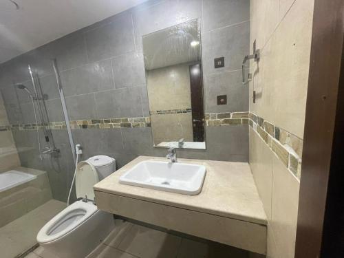 a bathroom with a sink and a toilet and a mirror at Adorable Master Room - Heart of Abu Dhabi in Abu Dhabi