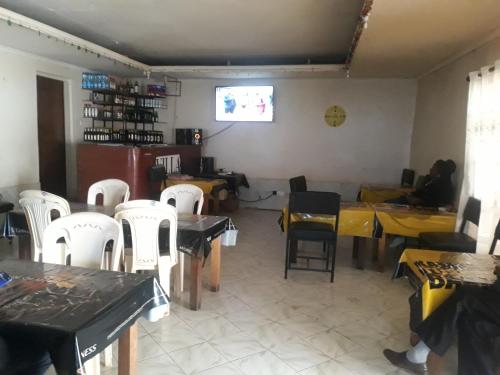 a restaurant with tables and white chairs and a room at RockVilla GuestHouse Njabini in South Kinangop