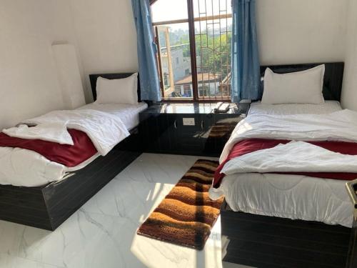 two beds sitting in a room with a window at Royalwood City Inn in Birātnagar