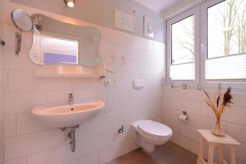 a white bathroom with a sink and a toilet at Hotel Garni Auszeit in Boltenhagen