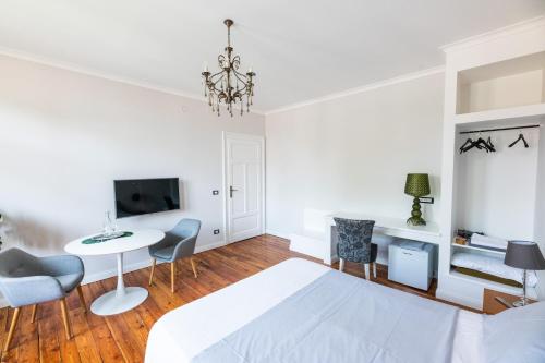 um quarto branco com uma cama branca, uma mesa e cadeiras em The Liberty Terrace em Udine