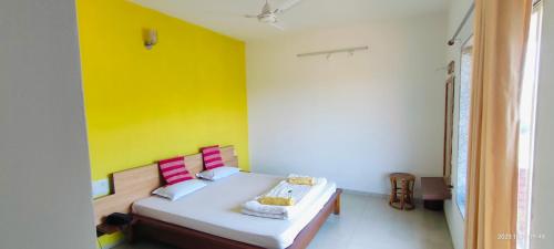 - une chambre dotée d'un lit avec un mur jaune dans l'établissement Konark Villa, à Mahabaleshwar