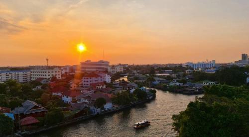 una puesta de sol sobre una ciudad con un río y edificios en NORN Rimkhlong Bangkok นอนริมคลอง en Bangkok Noi
