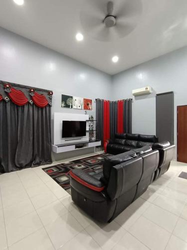 ein Wohnzimmer mit schwarzen Ledermöbeln und einem Flachbild-TV in der Unterkunft Kuantan Nadira Suite Homestay in Kuantan