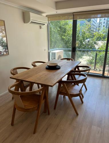 a wooden table and chairs in a room with a large window at Spacious apartment minutes from the CBD in Melbourne