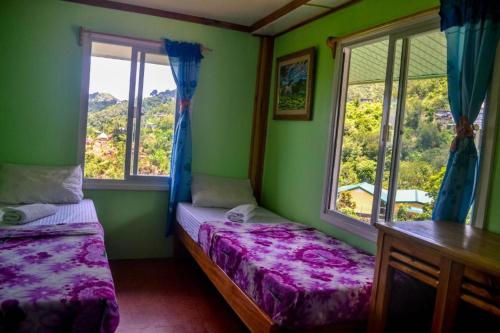 a bedroom with two beds and two windows at BANAUE EVERGREEN HOSTEL AND RESTAURANT in Banaue