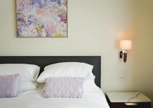 a bed with white pillows and a painting above it at Baan Naya ที่พักสัตหีบ in Ban Chang