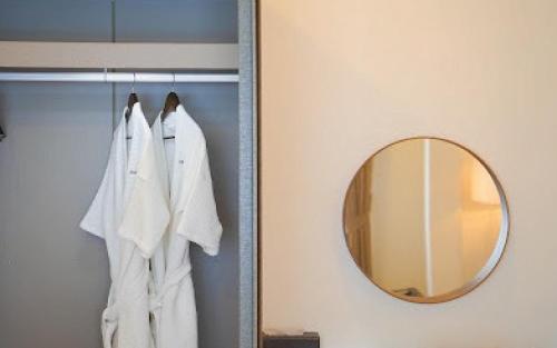 a bathroom with a mirror and a white robe at Baan Naya ที่พักสัตหีบ in Ban Chang