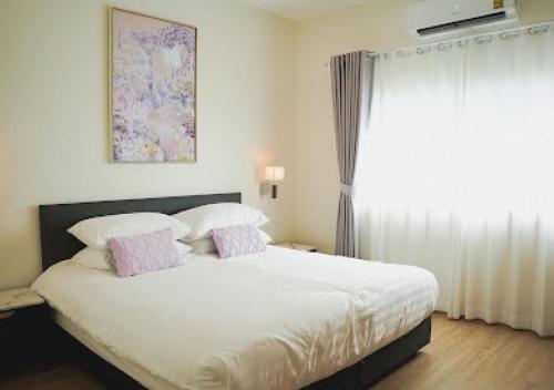 a bedroom with a bed with pink and white pillows at Baan Naya ที่พักสัตหีบ in Ban Chang