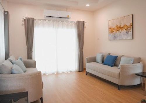 a living room with two couches and a window at Baan Naya ที่พักสัตหีบ in Ban Chang