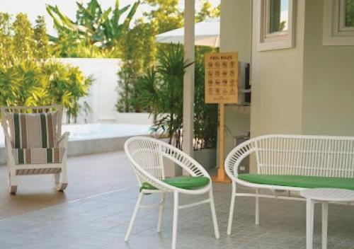 two white chairs and a table with a green seat at Baan Naya ที่พักสัตหีบ in Ban Chang