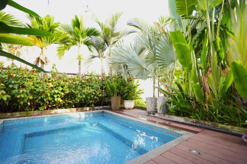 a swimming pool in a garden with palm trees at Prostyle Hotel Ho Chi Minh プロスタイルホテルホーチミン in Ho Chi Minh City