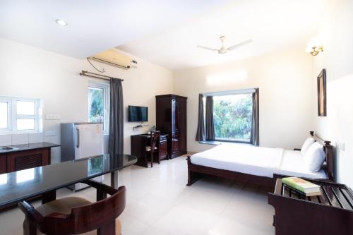 Schlafzimmer mit einem Bett, einem Schreibtisch und einem Tisch in der Unterkunft Sanctum Suites Indiranagar Bangalore in Bangalore