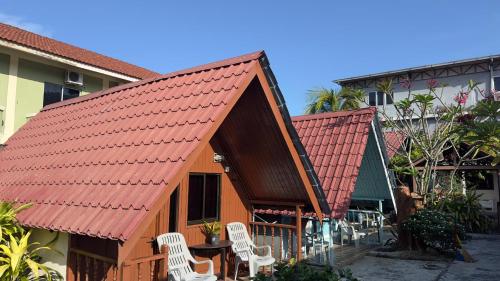 a house with an orange roof and white chairs at INTAN CHALEt in Pangkor