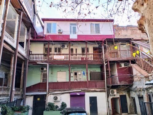 un edificio con balcones y un coche aparcado delante de él en LA CASA, en Tiflis