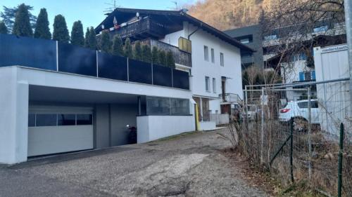 una casa blanca con garaje y valla en Plose Panorama House en Bressanone