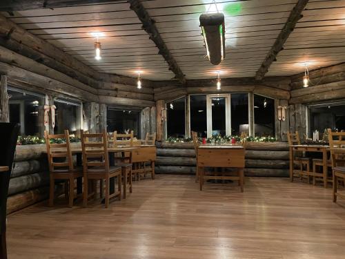 un restaurante con mesas y sillas de madera y ventanas en Skogen-Lodge en Koskullskulle