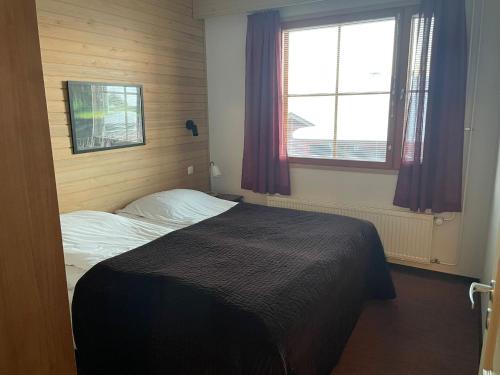 a bedroom with a bed and two windows at Viihtyisä lomahuoneisto Rukalla! in Kuusamo