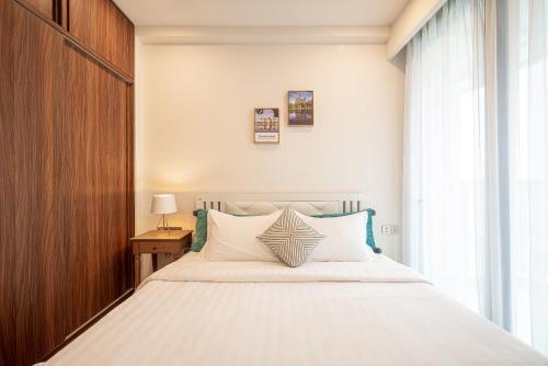 a bedroom with a large white bed with a window at Metropole Thu Thiem Condo Apartment in Ho Chi Minh City