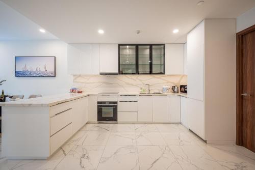 a kitchen with white cabinets and a tile floor at Metropole Thu Thiem Condo Apartment in Ho Chi Minh City