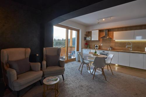 cocina y sala de estar con sillas y mesa en Donovaly Residence Apartment 111 en Donovaly